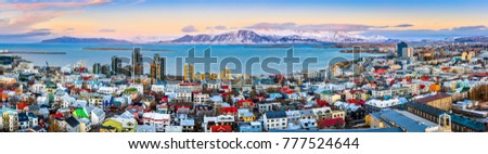 Aerial panorama of downtown Reykjavik at sunset with colorful houses and snowy mountains in the background