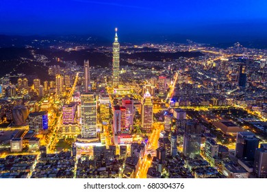 Aerial panorama over Downtown Taipei at night, capital city of Taiwan with view of prominent Taipei 101 Tower and busy street in Xinyi Financial District 