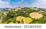 An aerial panorama view across the countryside towards the hilltop city of Urbino, Italy in summertime