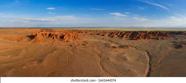 Aerial panorama view of the Bayanzag flaming cliffs at sunset in Mongolia, found in the Gobi Desert.