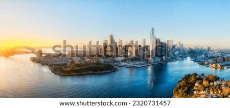 Aerial panoramic cityscape of City of Sydney Barangaroo harbour waterfront architecture landmarks at sunrise.
