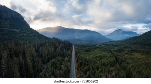 Aerial panoramic drone view of a scenic highway by the beautiful Canadian Landscape covered in clouds and fog. Taken in Vancouver Island, British Columbia, Canada.