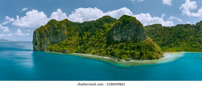 Aerial panoramic drone view of uninhabited tropical island with towering mountains and rainforest jungle surrounded by blue ocean - Shutterstock ID 1530439841