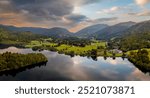 Aerial panoramic landscape of the village and lake of Grasmere in The Lake District National Park with a beautiful sunrise and calm water