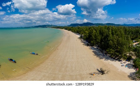 Aerial panoramic view of a beautiful tropical beach with traditional boats surrounded by lush greenery (Khao Lak, Thailand)