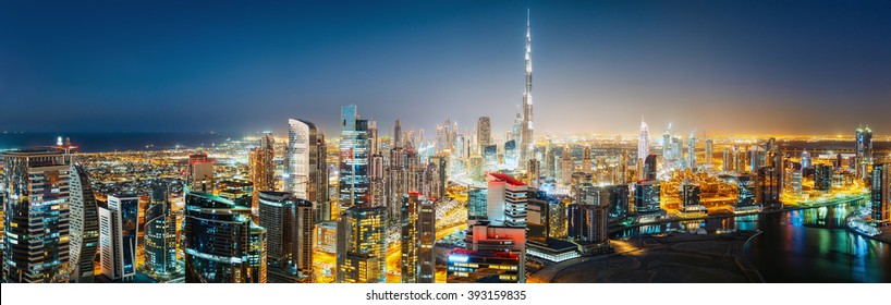 Aerial panoramic view of a big futuristic city by night. Business bay, Dubai, United Arab Emirates. Nighttime skyline. 
