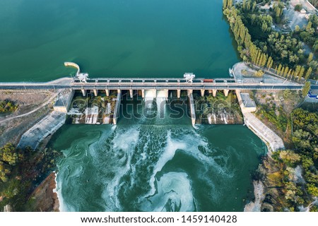 Aerial panoramic view of concrete Dam at reservoir with flowing water, hydroelectricity power station, drone shot.
