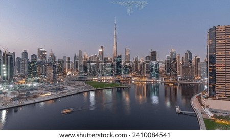 Aerial panoramic view to Dubai Business Bay and Downtown with the various skyscrapers and towers along waterfront on canal day to night transition timelapse. Construction site with cranes after sunset