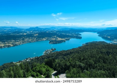 Aerial panoramic view of Lake Wörthersee seen from Pyramindenkogel in Carinthia, Austria. Serene turquoise waters, lush green forests and rolling hills of Austrian Alps. Charming lakeside village - Powered by Shutterstock