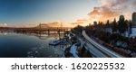 Aerial Panoramic View of the Modern City, Skytrain, Train and Fraser River during a colorful Sunset. Taken in New Westminster, Vancouver, British Columbia, Canada.