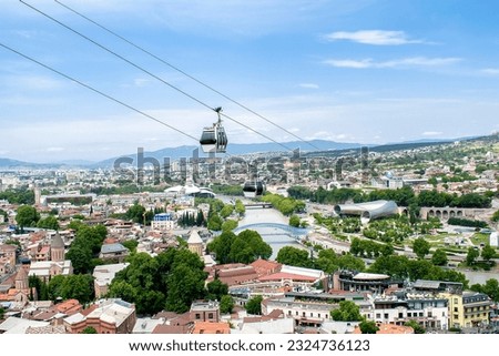 Aerial Panoramic view of old historic city, town of Georgia Tbilisi with Cable car machine close up on sunny day with river, bridge of Peace,Rike park,mosque and architecture buildings roofs.