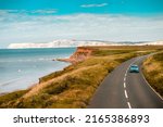 Aerial panoramic view of road with blue car on it with the Needles and sea view. The Isle of WIght, UK