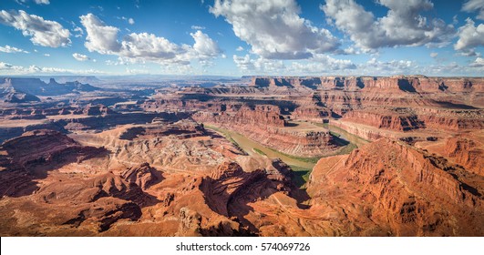 Aerial panoramic view of scenic Dead Horse Point State Park with famous Colorado river flowing on a beautiful sunny day with blue sky and dramatic clouds in summer, Utah, American Southwest, USA