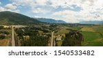 Aerial Panoramic View of Small Town, Creston, during a sunny and cloudy summer day. Located in the Interior of British Columbia, Canada.