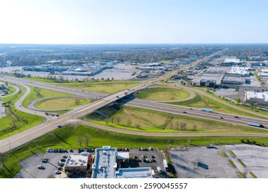 Aerial perspective of complex traffic interchange with busy roads, commercial areas, green spaces on America