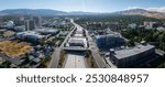 Aerial perspective of Reno, Nevada, featuring the Silver Legacy Resort Casino, urban buildings, a major highway, and the Sierra Nevada mountains.