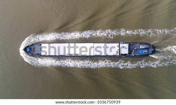 Aerial photo of barge moving over canal\
this flat-bottomed boat is mainly built for river and canal\
transport of heavy goods most barges are\
self-propelled