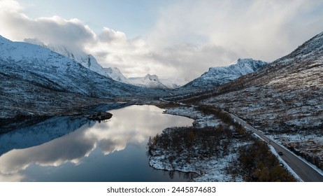 Aerial photo of a calm Norwegian mountain alpine lake in the Winter in the Arctic Circle of Norway.  Cloudy skies with snowcapped mountains.  Shot on a DJI Drone. - Powered by Shutterstock