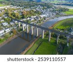 Aerial photo of Calstock Viaduct in Cornwall, England, spanning the River Tamar. The shot captures the impressive 12-arch stone railway bridge set against the scenic countryside