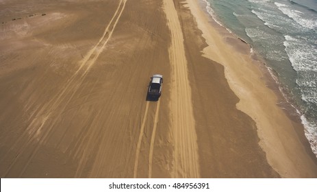 Aerial Photo From Flying Drone Of A Riding Rental Car On A Sandy Beach Near Beautiful Sea With Calm Waves. Active Sport Recreation With Pickup Machine Near Indian Ocean During Trip To Thailand