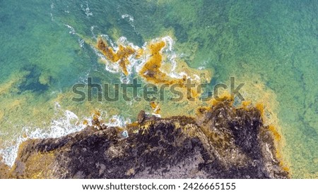Aerial photo the ocean waves braking on the shores in Canary Islands - Lanzarote: from above with strong waves in blue torquise ocean Cliffs and rocks with ocean by drone. Green Yellow contrast