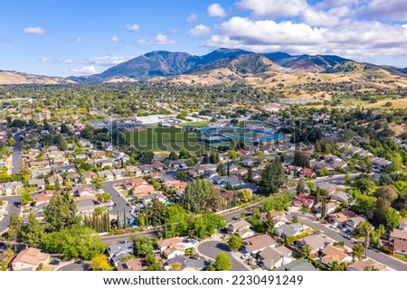 Aerial photo over the city of Concord, California with houses in the foreground and green trees with Mt.Diablo in the background and a blue sky