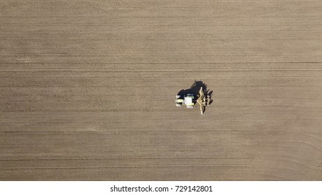 Aerial Photo Overhead Tractor And Tiller Harrowing Ploughed Soil In Farm Field