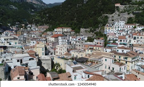 Aerial Photo Of Rural Mountain Town Showing Buildings And Bed And Breakfast Roof Terrace With Several Seats For Sun Bathing And Relaxing In Background Tall Mounts Surrounding Urban Area