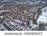 Aerial photo of a snowy day in the city of Leeds in the UK, showing rows of terrace houses with snow covered roofs in the Village of Beeston in the winter time