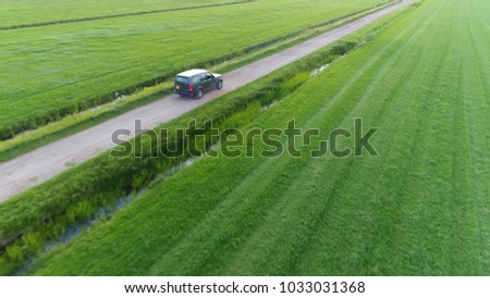 Aerial photo of unpaved road and off road vehicle following the all wheel car rural area drone view flight backwards away from the SUV beautiful nature and outdoors area typical offroad SUV scene