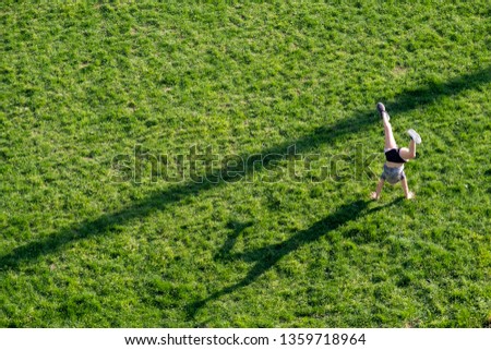 An aerial photo of a woman doing a handstand in a field of grass
