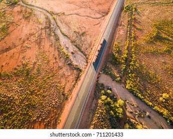 Aerial Photograph Of Australian Outback And Dry Road With Roadtrain Surrounded By Gum Trees And Spinifex.