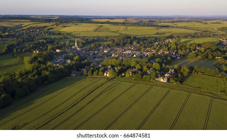 Aerial Photograph Of Small Town Burford In Oxfordshire, Cotswolds, Surrounded By Forest And Agricultural Fields.