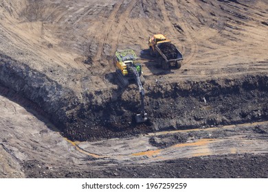 An aerial photograph taken from a helicopter of an excavator and dump truck at a brownfield landfill site in South Wales, UK. Soil, mud and refuse. 