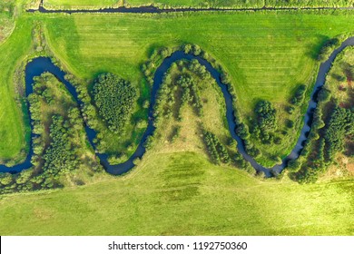 Aerial photograph of winding river in rural landscape. Small river winding in green grass field