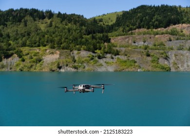 Aerial Photography From A Bird's Eye View, A Helicopter Flies In The Forest, Photographs The Nature Of The Lake. In The Summer Afternoon In The Forest, A Professional Drone With A 4K