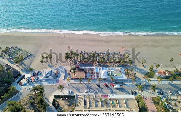 Aerial photography of\
Burriana beach with facilities around all needs as sunbeds,\
restaurants, playground for kids, car park in the tourist town of\
Nerja Spain, March 2019