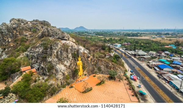 aerial photography the golden bas relief Buddha\
statue in front the cliff at Khao Ngu cave temple.Khao is meant\
mountain,Ngu is mean snake.\
this temple is mean snakes inside the\
cave at this mountain