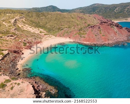 Aerial photography of the incredible landscape of turquoise waters and cliffs of Cala del Pilar, in the northern part of Menorca, Balearic Islands. A paradise of turquoise blue waters, red sand.