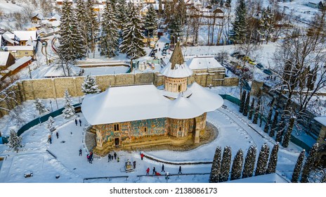 Aerial photography of Voronet Monastery, located in Suceava county, Romania in winter, sunny day with snow. Photo was shot from a drone with camera tilted down towards the building.