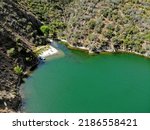 Aerial picture of private bay at Pyramid Lake California. Isolation stranded on green turquoise beach in San Bernadino National Forest. Escape into paradise with blue fishing boat green surroundings