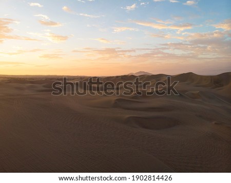 Aerial postcard panorama sunset view of isolated vast dry sand dunes desert of Huacachina Ica Peru South America