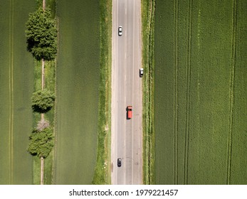 Aerial. Red truck and other cars driving along the rustic asphalt road between fields. View above from drone. Russia. Rostov region.