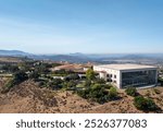 Aerial Ronald Reagan President Library and museum on top of a hill with multiple structures and green vegetation. 