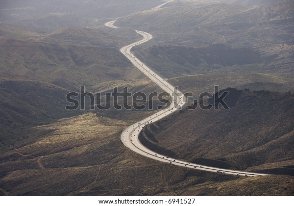 Aerial of Route 14 with traveling\
vehicles through rural California landscape,\
USA.