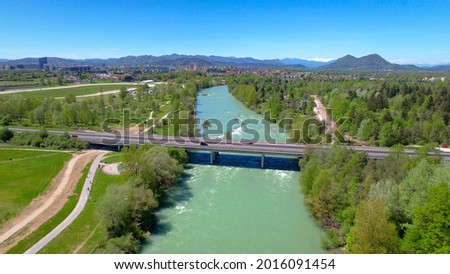 AERIAL: Scenic drone point of view of a highway crossing the emerald river crossing the lush green Slovenian landscape. Sava river coursing through the vibrant Ljubljana suburbs on sunny summer day. Stok fotoğraf © 