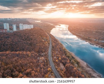 Aerial scenic panorama of railroad at city suburbs. Majestic sunset clouds reflecting in the river waters