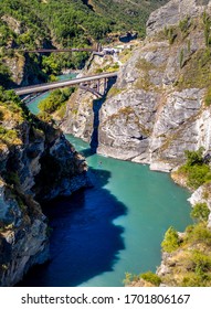 Aerial Shoot Of Winding Kawarau River And Two Overhead Bridges On A Sunny Summer Day.