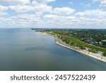 aerial shot along the coast of Lake Pontchartrain with homes, lush green trees, plants and grass, rippling water, blue sky and clouds in New Orleans Louisiana USA