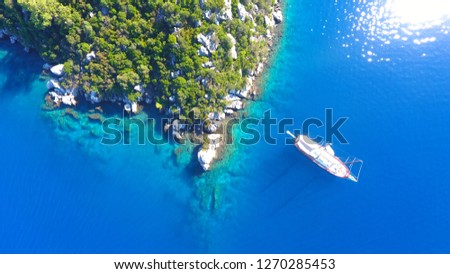 Aerial shot of beautiful blue lagoon and nature at hot summer day with sailing boat at open sea. Top view of gulet wooden yacht in Marmaris Mugla Turkey at Aegean Sea Turkey